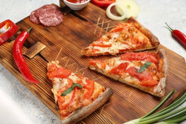 Lezzetli pizza dilimleri ve beyaz grunge arka planda malzemelerle ahşap tahta.