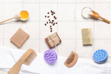 Saç derisi masaj aletleri, şampuan çubukları, fırçalar ve beyaz fayans zemininde bal.