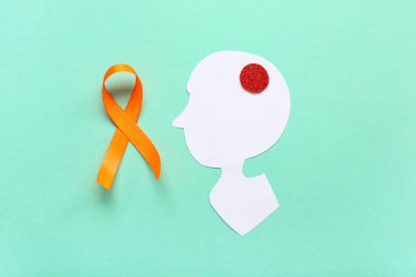 Kağıt insan kafası ve turkuaz arka planda turuncu kurdele. Çoklu Skleroz Farkındalık Ayı