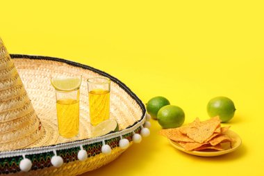 Sarı arka planda tekila, limon ve şapka.