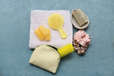 Saç fırçaları, ipek tokalar ve mavi grunge arka planda sabun bulunan kozmetik çanta.