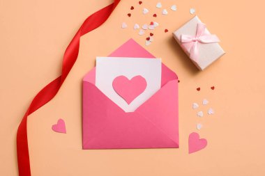 Kağıt kalpli zarf ve bej arka planda hediye kutusu. Sevgililer Günü kutlaması