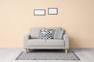 İçinde bej kanepe olan şık bir oda ve aydınlık duvarda asılı resimler.