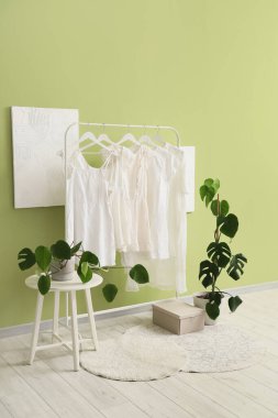 Beyaz elbiseli ve palmiye bitkilerli bir giyim mağazası.