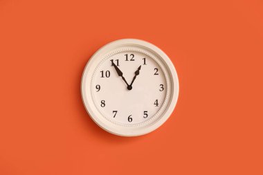 Turuncu duvarda asılı şık bir saat