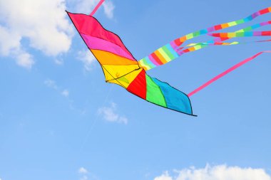 Güneşli bir günde mavi gökyüzünde uçan renkli uçurtma