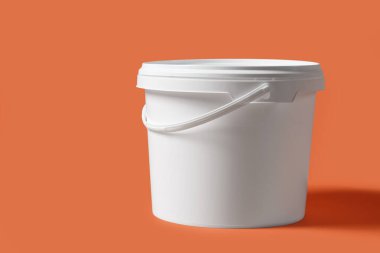 Turuncu arka planda plastik boya kovası