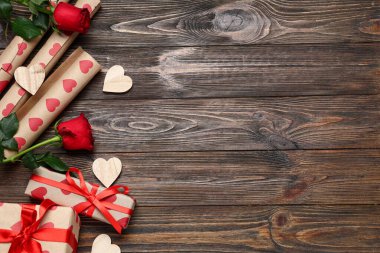 Hediye kutuları, ambalaj kağıtları ve tahta arka planda gül çiçekleri olan kompozisyon. Sevgililer Günü kutlaması