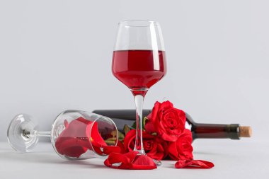 Kırmızı şarap kadehleri ve beyaz arka planda gül yaprakları, yakın plan. Sevgililer Günü kutlaması