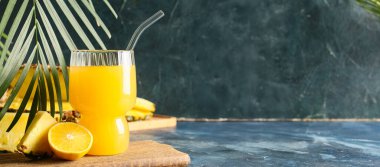 Mavi grunge arkaplanda bir bardak lezzetli ananas suyu ve metin için yer var.