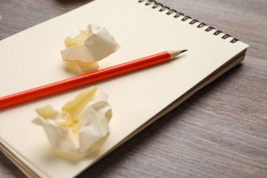 Ahşap zemin üzerinde buruşuk kağıt ve kalem olan defter.