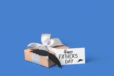 Yazılı kağıt Mutlu Babalar Günü, bıyık ve mavi arka planda hediye