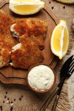 Tahta tahtada limon ve soslu kızarmış morina balığı, yakın plan.