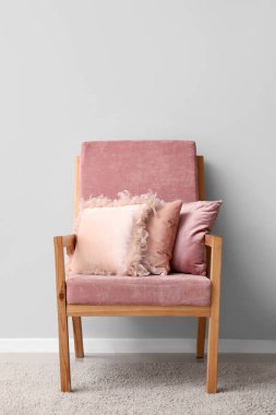 Odada ışıklı duvarın yanında rahat yastıklı bir koltuk.