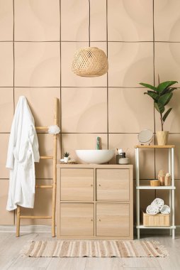 Bornozlu, lavabolu ve ahşap dolaplı banyo aksesuarları.