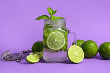 Mason kavanozu soğuk mojito ve mor arka planda limon.