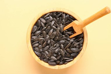 Bej arkaplanda ayçiçeği tohumları olan bir kase