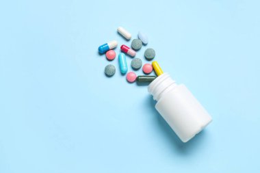 Mavi arka planda farklı dağınık haplarla dolu kavanoz.