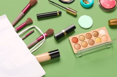 Yeşil arka planda makyaj malzemesi olan alışveriş torbası.