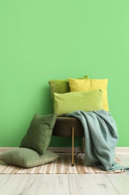 Ottoman with soft cushions near green wall