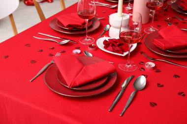 Sevgililer Günü kutlaması için yemek masası, mumlar ve kağıt kalpler.