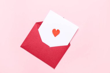 Zarflı kompozisyon, kart ve pembe arka planda kağıt kalp. Sevgililer Günü kutlaması