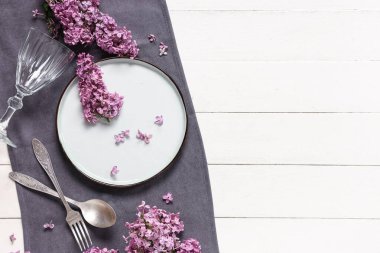 Beyaz ahşap arka planda leylak çiçekleri olan güzel bir masa.