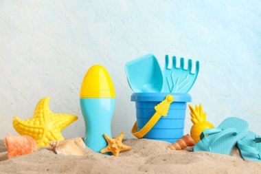 Mavi grunge arka planındaki çocuklar için kum, güneş kremi ve plaj aksesuarlarıyla güzel bir kompozisyon