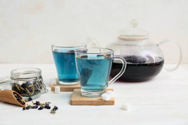 Kelebekli kavanoz bezelye çiçeği çayı ve beyaz arka planda mavi organik çay, yakın plan.