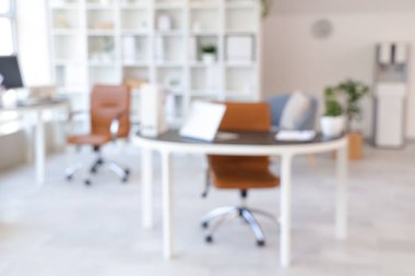 Çalışma alanları, raf ünitesi ve koltukları olan açık uzay ofisinin içi, bulanık görünüm