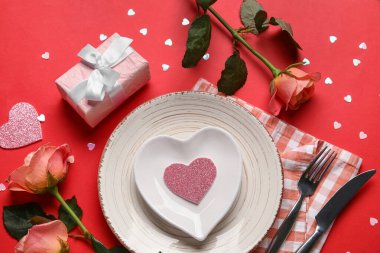 Hediye kutusu ve kırmızı arka planda güzel güller olan şık bir masa. Sevgililer Günü kutlaması