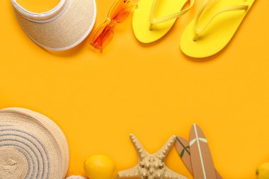 Parmak arası terlikli denizyıldızı, turuncu arka planda limon ve plaj aksesuarları