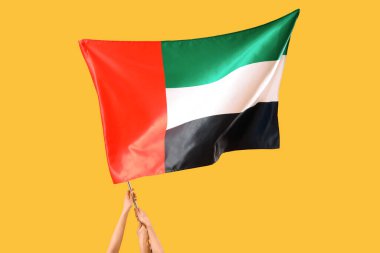 Sarı arka planda bayrak sallayan kadın elleri