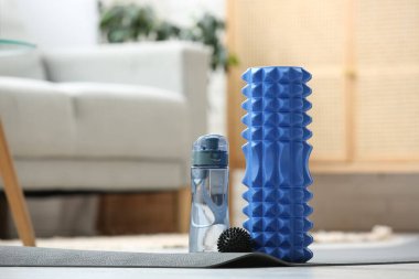 Oturma odasındaki yoga minderinde su ve top dolu köpük silindirli.
