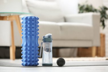 Oturma odasındaki yoga minderinde su ve top dolu köpük silindirli.