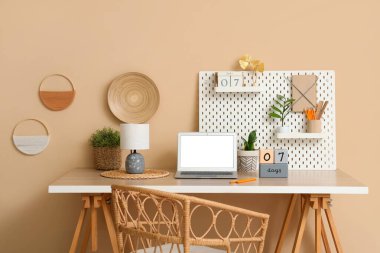 Modern dizüstü bilgisayarı, küp takvimi ve renk duvarının yanındaki tahta ile şık bir iş yeri