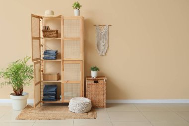 Odanın içindeki bej duvarın yanında giysi ve sepetli ahşap dolabı aç.