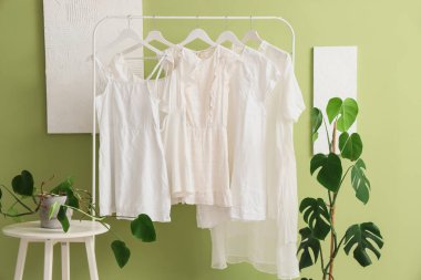 Beyaz elbiseli ve palmiye bitkilerli bir giyim mağazası.