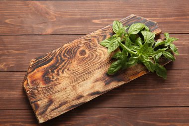 Ahşap arka planda taze fesleğen yapraklarıyla tahta kesme.