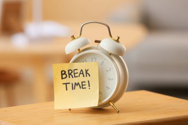 Çalar saat ve yapışkan not. Ofisteki masada mesajlaşma zamanı.