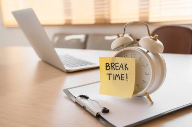 Alarm saati ve yapışkan notla yazılan BREAK Time ve masadaki pano