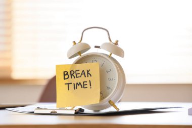 Alarm saati ve yapışkan notla yazılan BREAK Time ve masadaki pano