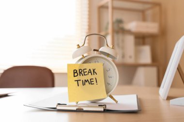 Alarm saati ve yapışkan notla yazılan BREAK Time ve masadaki pano