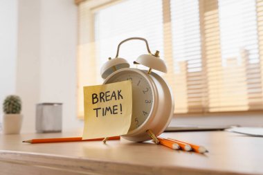 Alarm saati ve yapışkan notla yazışma molası zamanı ve ofis masasında kalemler