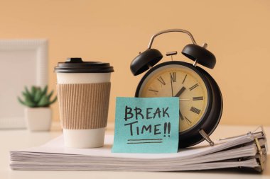 Çalar saat ve yapışkan notla birlikte kısa bir mola zamanı, ofiste bir fincan kahve ve kağıt çarşaf.