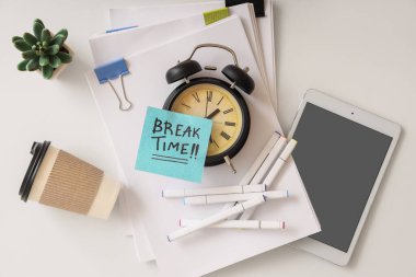 Çalar saat ve yapışkan notla birlikte kısa mesaj zamanı, kırtasiye malzemesi, tablet bilgisayar ve beyaz arkaplanda bir fincan kahve