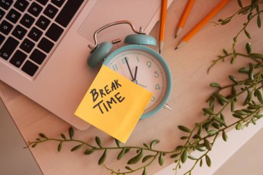 Alarm saati ve yapışkan notla yazılan BREAK Time ve masadaki laptop, üst görünüm