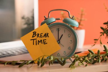 Çalar saat ve yapışkan not. Ofisteki masada mesajlaşma zamanı.