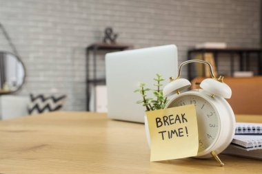 Çalar saat ve yapışkan not. Ofisteki masada mesajlaşma zamanı.