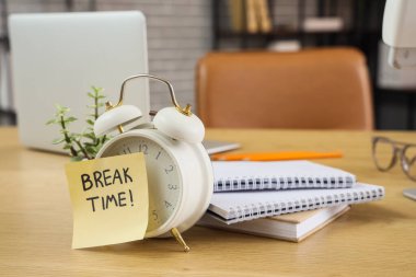 Alarm saati ve yapışkan notla yazışma zamanı ve masadaki not defterleri